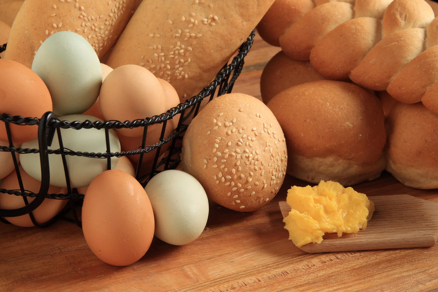 Buns and braided rolls in a basket with farm eggs