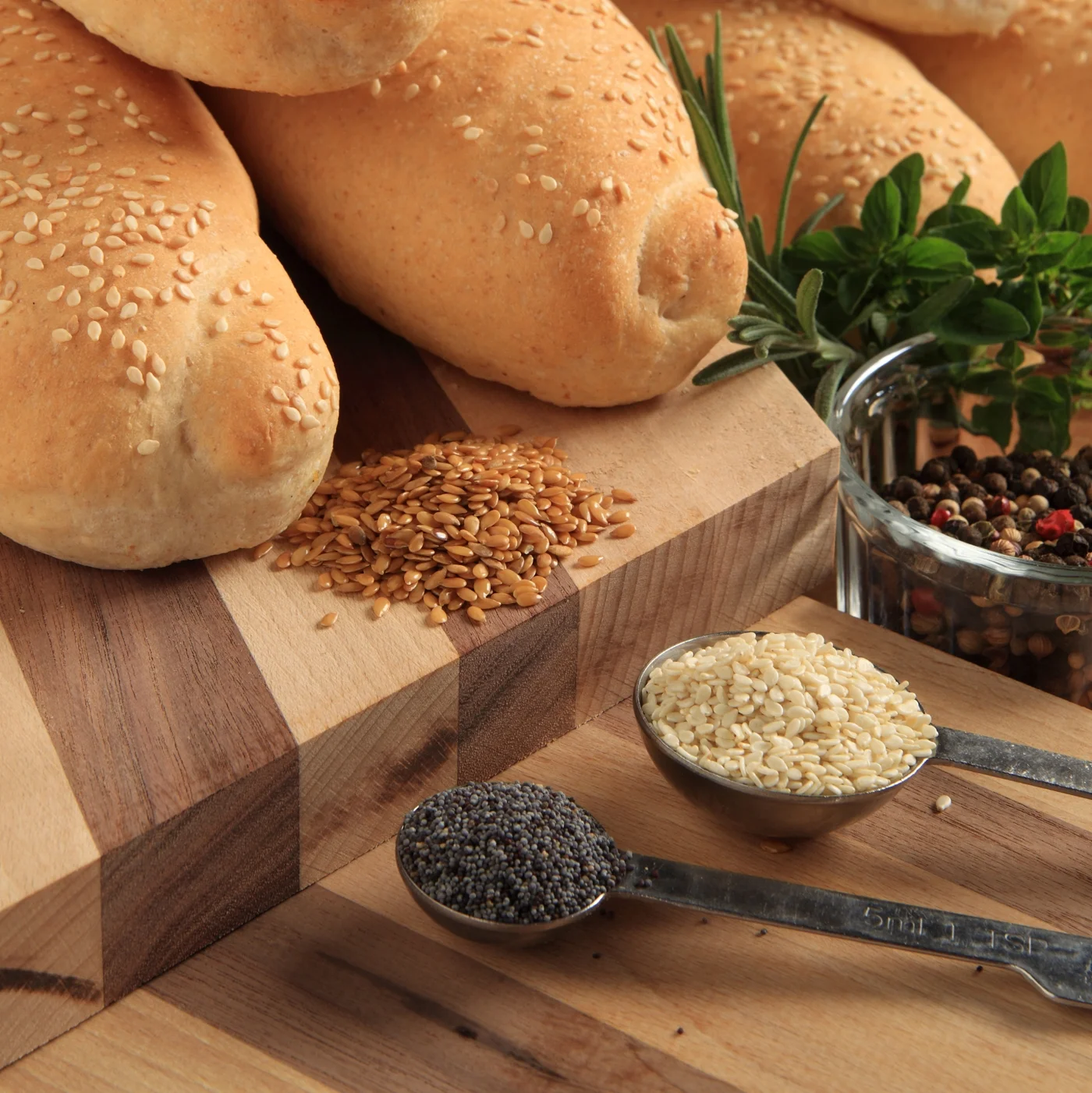 Seeded hoagie rolls with bowls of seeds